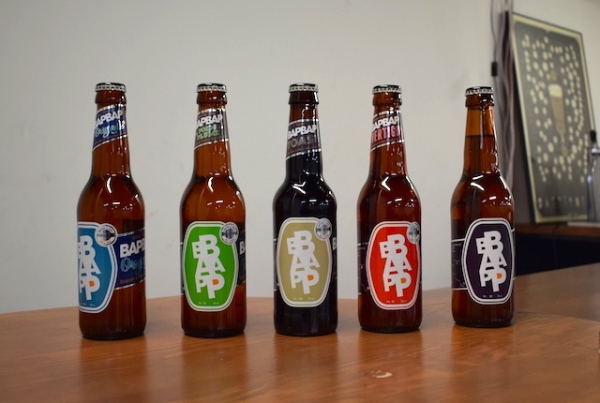 Six bouteilles de bière alignées sur le comptoir, elles ont toutes une couleur d'étiquettes différentes
